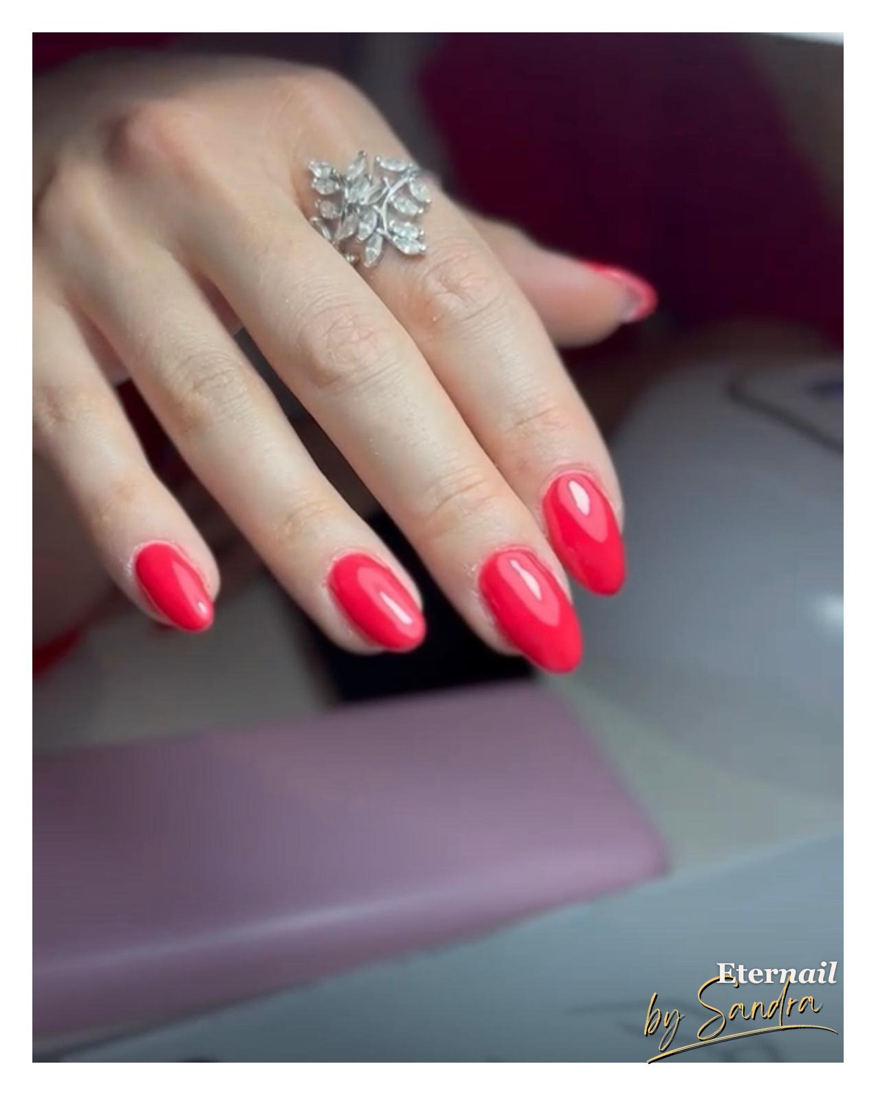 Glossy red almond-shaped gel manicure, close-up