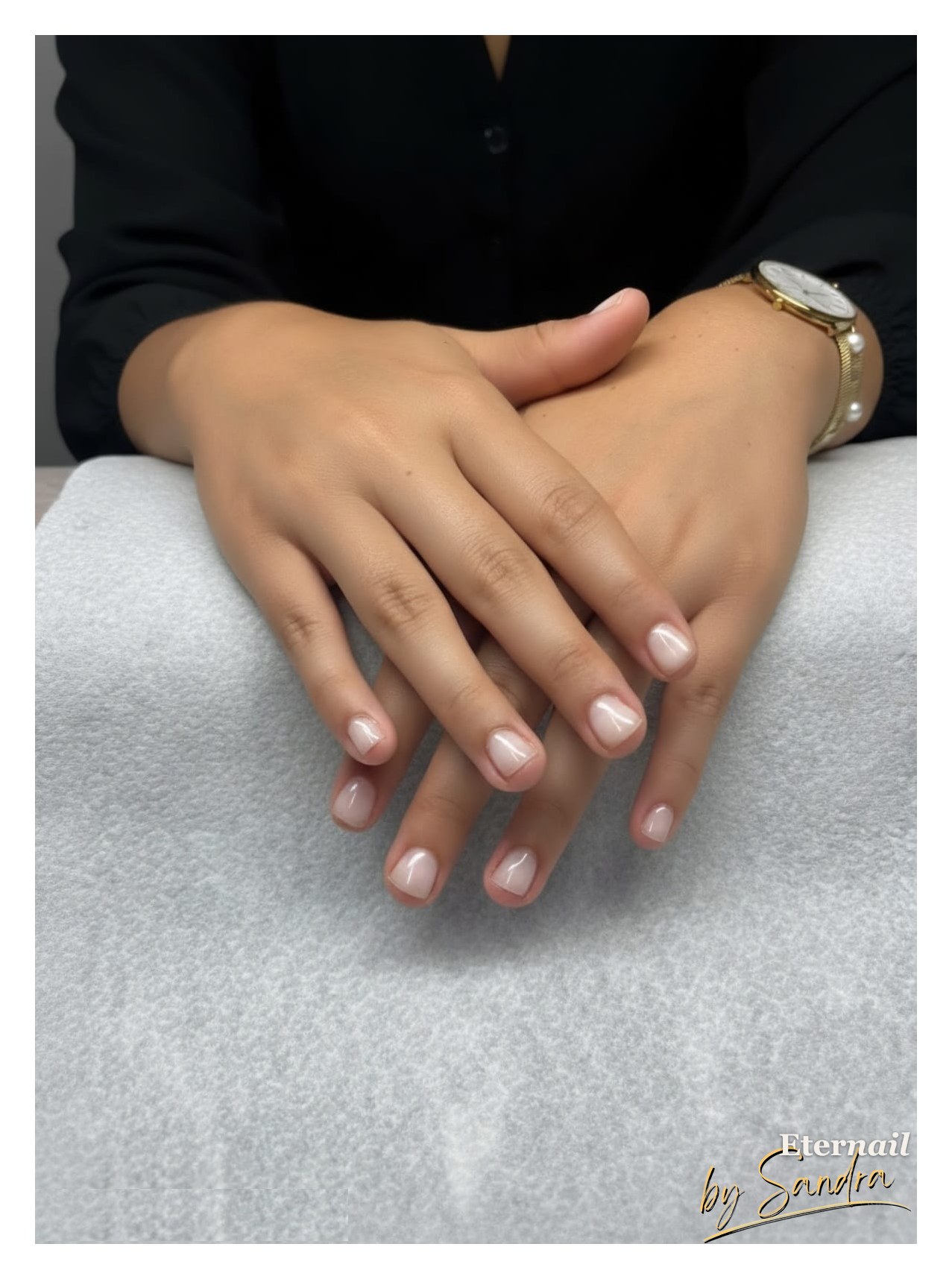 Soft pink glossy manicure, hands crossed and resting